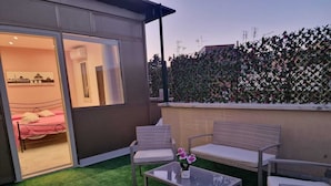 A balcony with a bed, a sofa, and a table.
