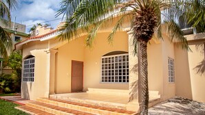 A two-story house with a tiled entrance, a palm tree, and a window with bars. - CASA BENCHITO (Tulum)
