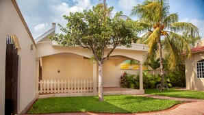 A courtyard with a white picket fence, a palm tree, and a bicycle. - CASA BENCHITO (Tulum)