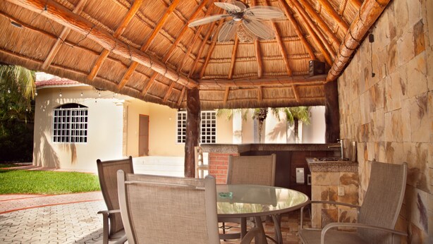 An outdoor patio with a thatched roof, a round table, and several chairs. - CASA BENCHITO (Tulum)