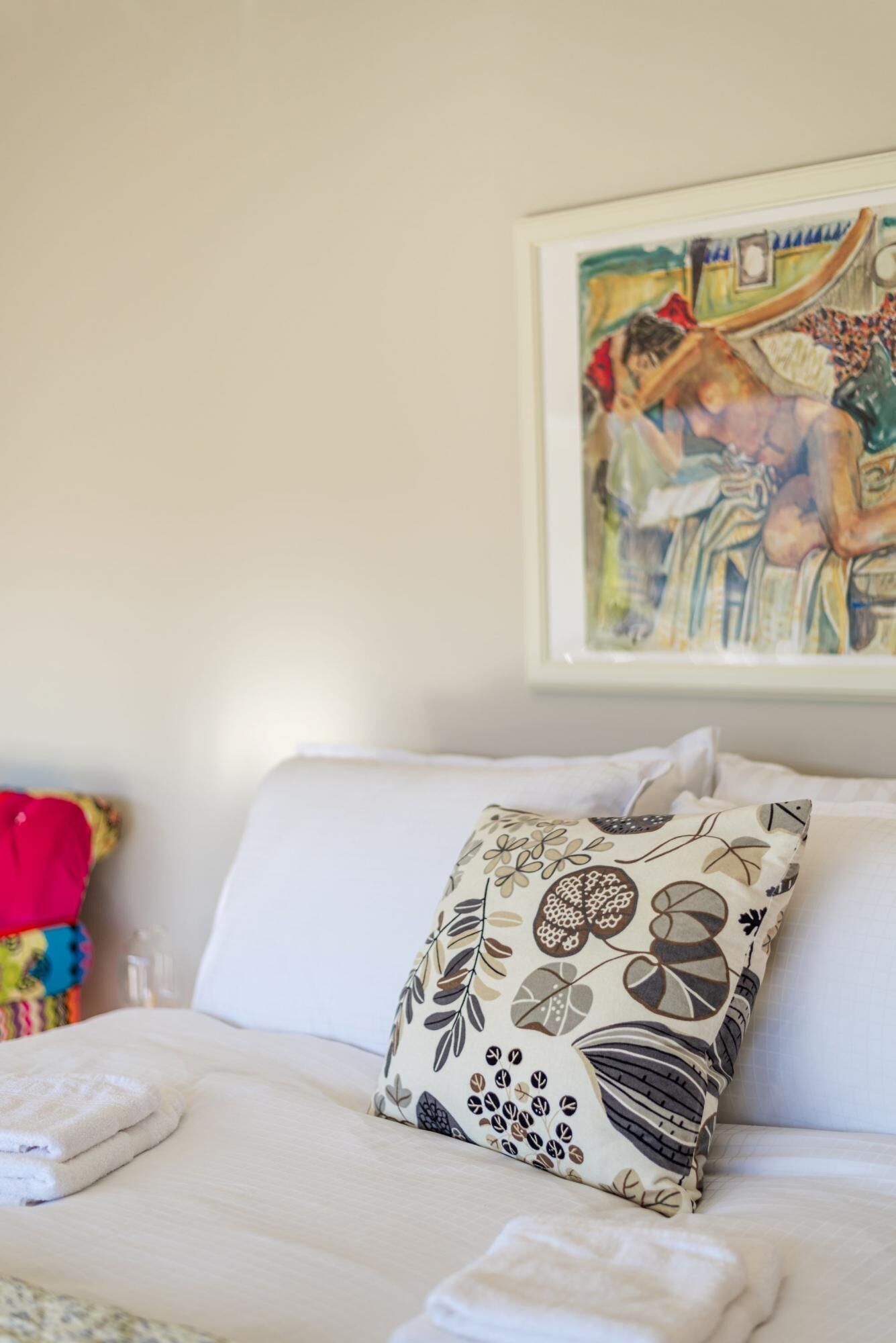 Un lit avec un oreiller blanc et une couverture colorée.