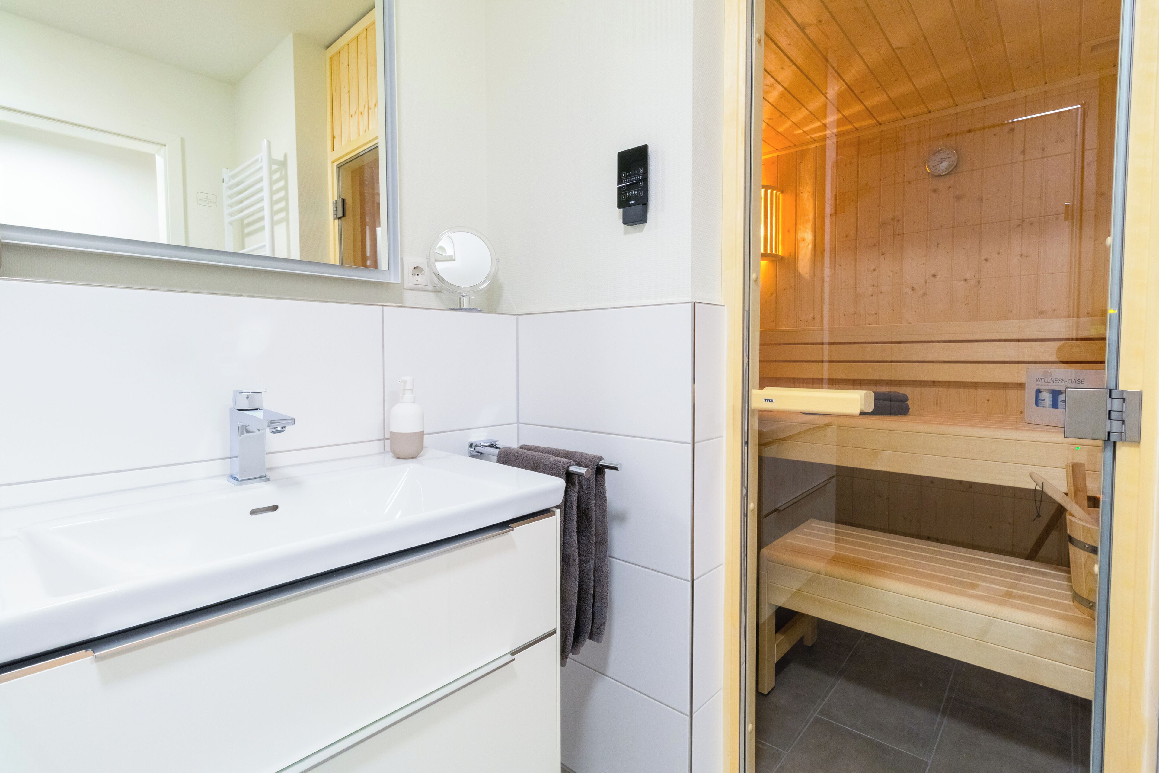 Ein modernes Badezimmer mit einem weißen Waschtisch, einem Spiegel und einem Handtuchhalter.