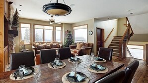 A dining area with a wooden table set for six, a Christmas tree, and a staircase leading to another level. - Dwight Out Chalet w/Hot Tub (Beaverdell)