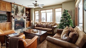 A cozy living room with leather furniture, a stone fireplace, and a Christmas tree. - Dwight Out Chalet w/Hot Tub (Beaverdell)