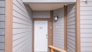 A narrow entrance with a white door, a bench, and a wall-mounted light fixture.