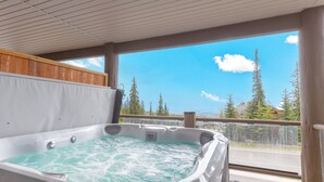 A hot tub with a view of a forest and mountains.