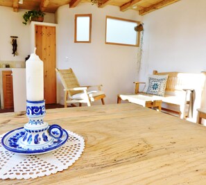 A wooden table with a white doily, a blue and white candle holder, and two white chairs.