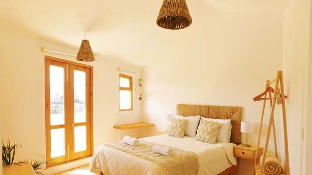 Una camera da letto con un letto di legno, un lampadario, una panca di legno e un'altalena di legno.