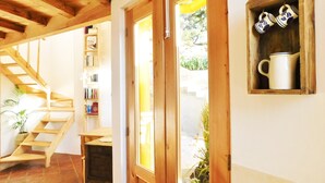 Una scala in legno, una porta con un vetro e uno scaffale con tazze.