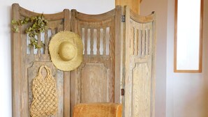 Una sedia di legno rustica di fronte a un pannello di legno con un cappello e una borsa intrecciati appesi.