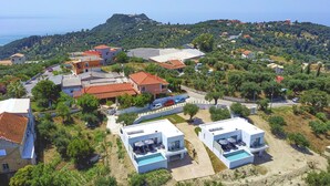 Un quartier résidentiel en bord de mer, avec des maisons modernes, une piscine et une vue sur la mer.