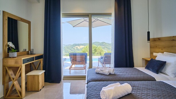 Une chambre avec un grand lit, un bureau en bois, une chaise et une vue sur l’extérieur.