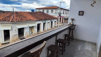 Un balcón con vistas a edificios, un farol colgante y una zona de bar con taburetes.