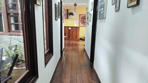 A hallway with wooden flooring, framed artwork on the walls, and a reception desk in the distance. - Pousada Flor de Lis  (Diamantina)