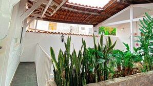 A covered outdoor area with a stone wall and various plants. - Pousada Flor de Lis  (Diamantina)