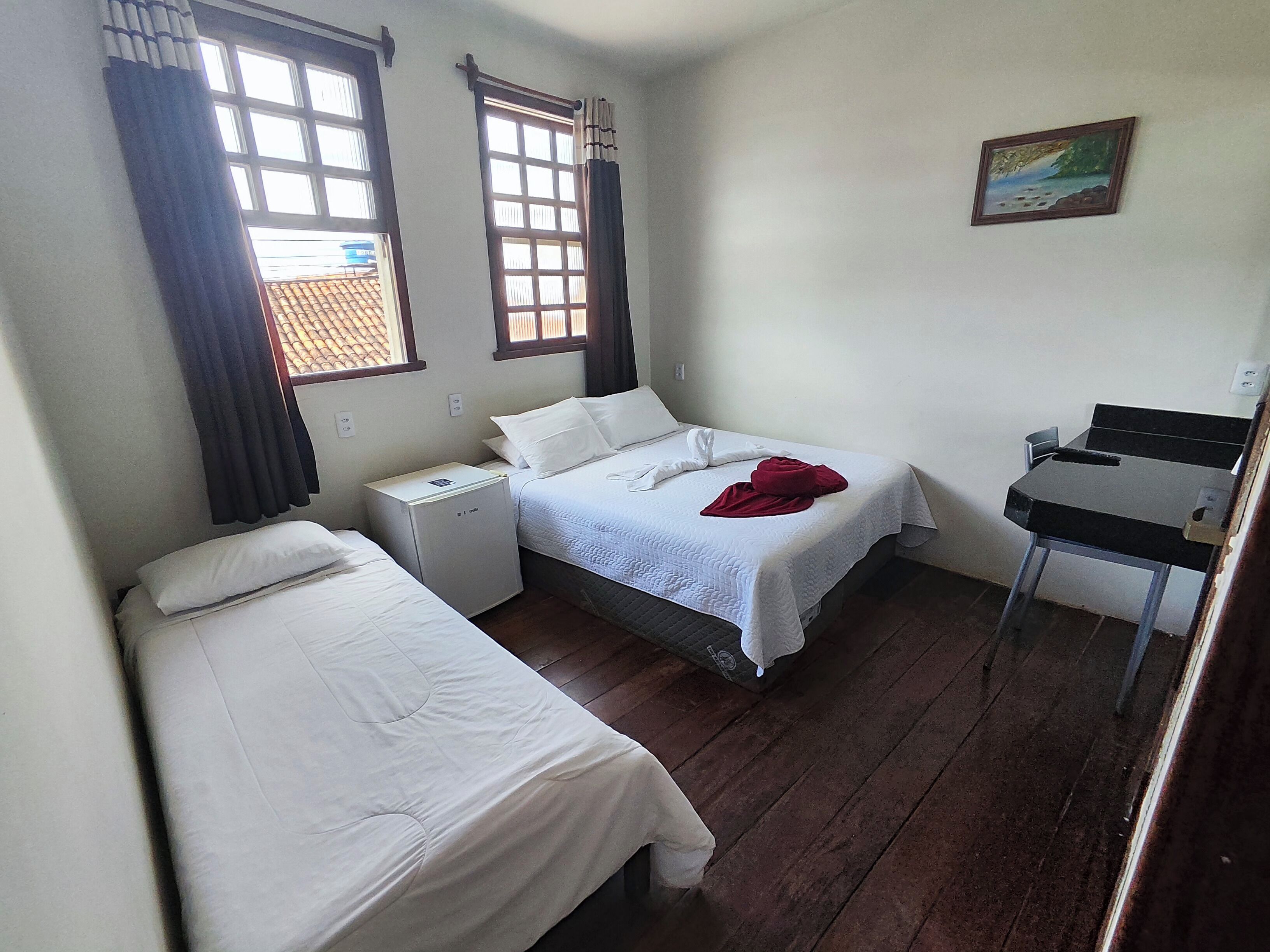 A small, tidy room with two single beds, a desk, and a chair.