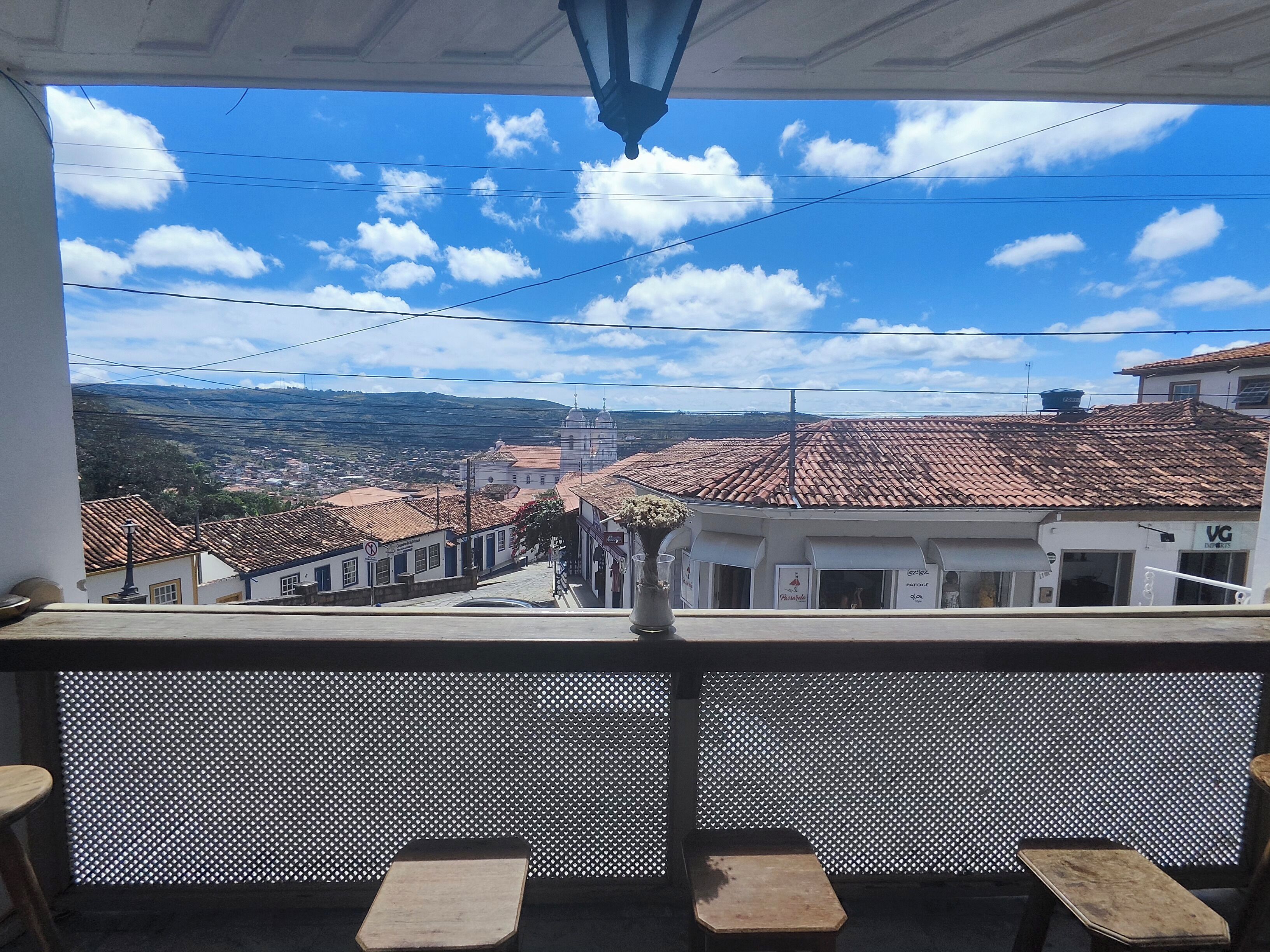 A balcony with a view of a town, a tiled roof, and a building with a sign.
