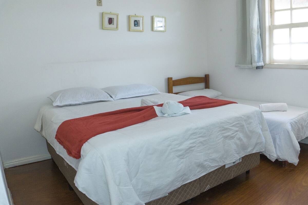 A room with two beds, a wooden headboard, and a window with curtains.