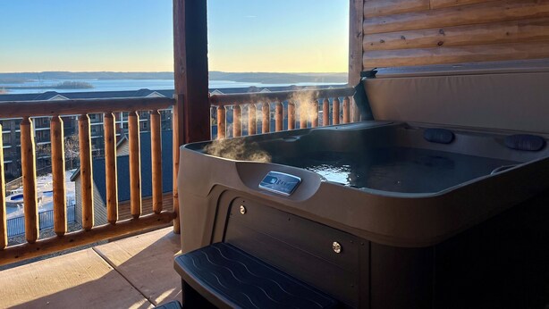 Un jacuzzi en un balcón con vistas a un paisaje nevado y un cielo despejado.