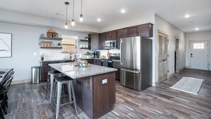 Una cocina moderna con una isla central, electrodomésticos de acero inoxidable y una zona de asientos con taburetes de bar.