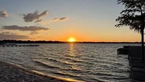 Un atardecer sobre una playa tranquila con un muelle que se adentra en el agua.