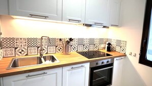 Een moderne keuken met witte kasten, een roestvrijstalen spoelbak en een ingebouwde oven.