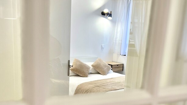 Een moderne hotelkamer met een bed, nachtkastjes en een bijzetmeubel.