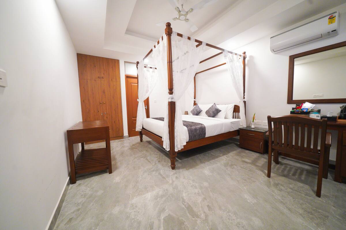 Une chambre à coucher comprenant un lit à baldaquin, un bureau en bois, une chaise et une armoire.