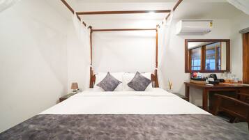 Un dormitorio con una cama con dosel, un escritorio con silla, un espejo y una mesita de noche con lámpara.
