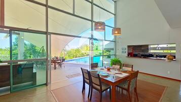 Uma sala de jantar ampla com vista para uma piscina e área externa com assentos.