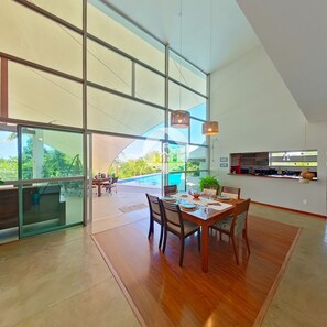 A spacious dining area with a view of a swimming pool and outdoor seating.