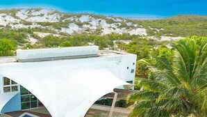 A modern building with a white exterior, a curved roof, and a view of a mountainous landscape.