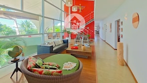A spacious living area with a large window, a staircase, and a red accent wall.