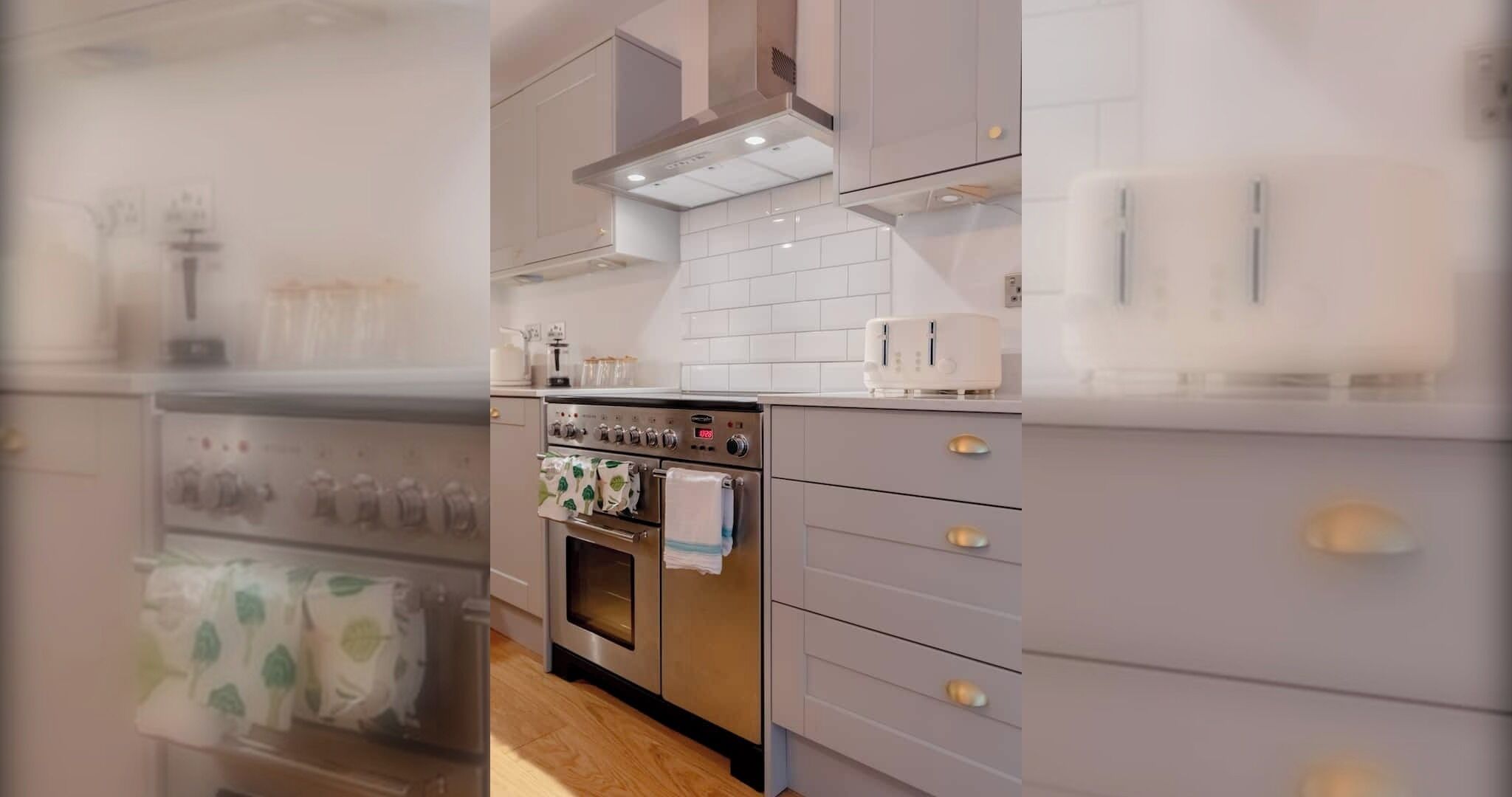 A modern kitchen with a stainless steel oven, white cabinets, and a tiled backsplash.