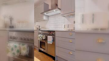 A modern kitchen with a stainless steel oven, white cabinets, and a tiled backsplash.
