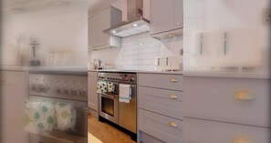 A modern kitchen with a stainless steel oven, white cabinets, and a tiled backsplash.