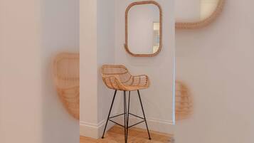 A wicker chair with a metal frame, positioned in front of a wall-mounted mirror.