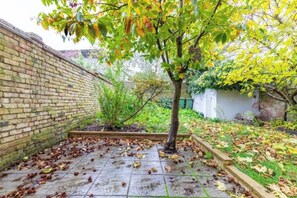 A brick wall, a tree, and a garden area with fallen leaves.