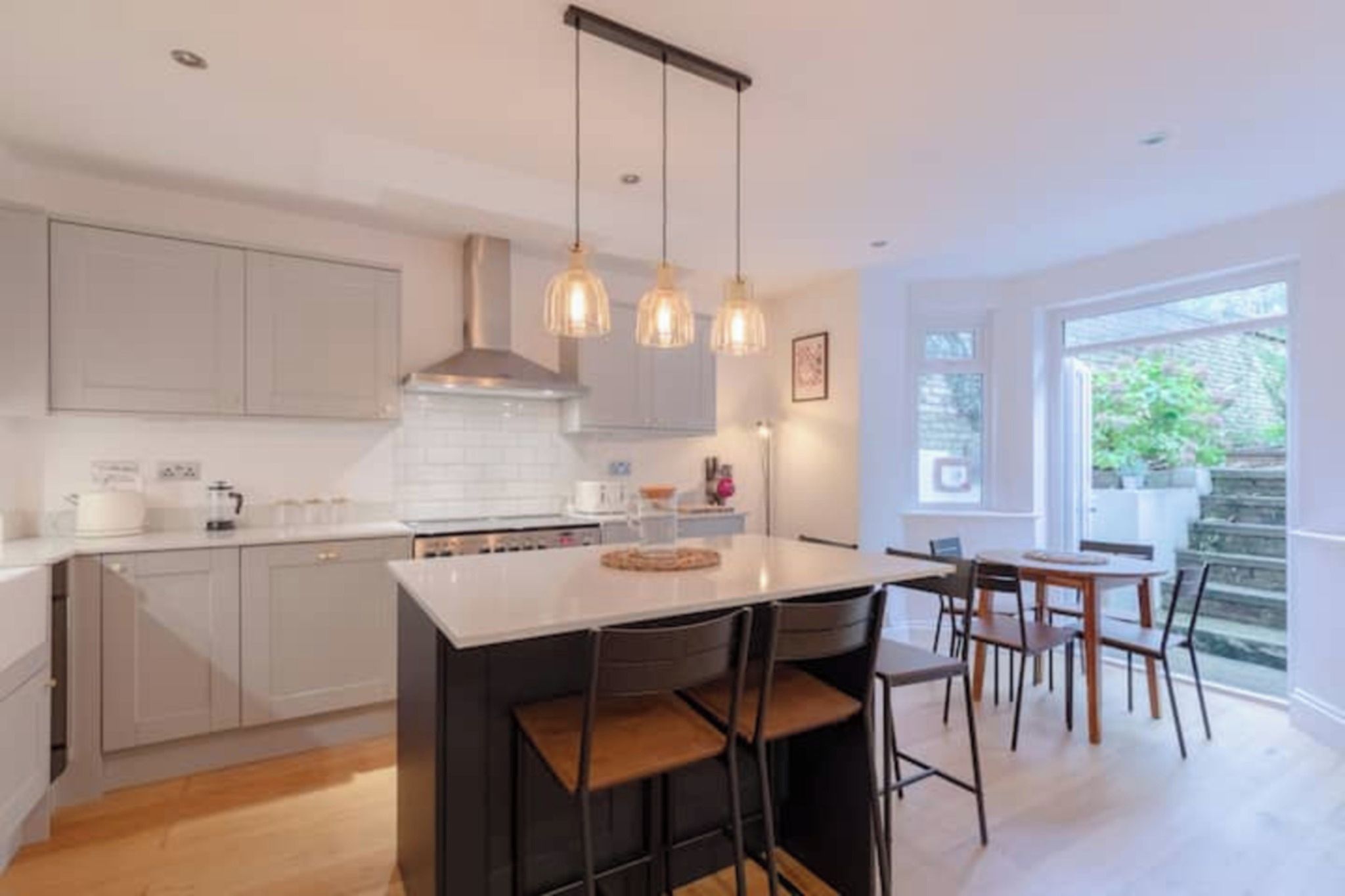 A modern kitchen with a central island, pendant lighting, and a view of the outdoors.