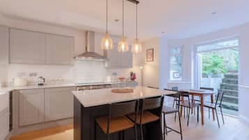 A modern kitchen with a central island, pendant lighting, and a view of the outdoors.