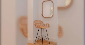 Een rieten stoel met metalen frame, geplaatst voor een spiegel die aan de muur hangt.