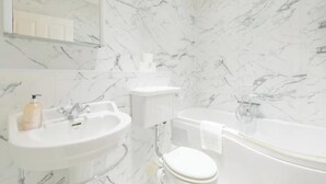 A bathroom with a white sink, toilet, and bathtub. - Stylish Garden Home 2 BDR Wimbledon (London)