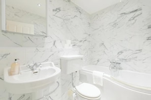 A bathroom with a white sink, toilet, and bathtub. - Stylish Garden Home 2 BDR Wimbledon (London)