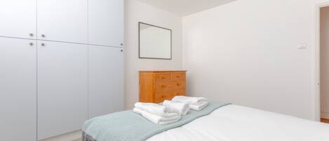 A bedroom with a bed, a wardrobe, and a dresser.