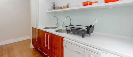 Una cocina con dos fregaderos, un escurreplatos y un lavavajillas.