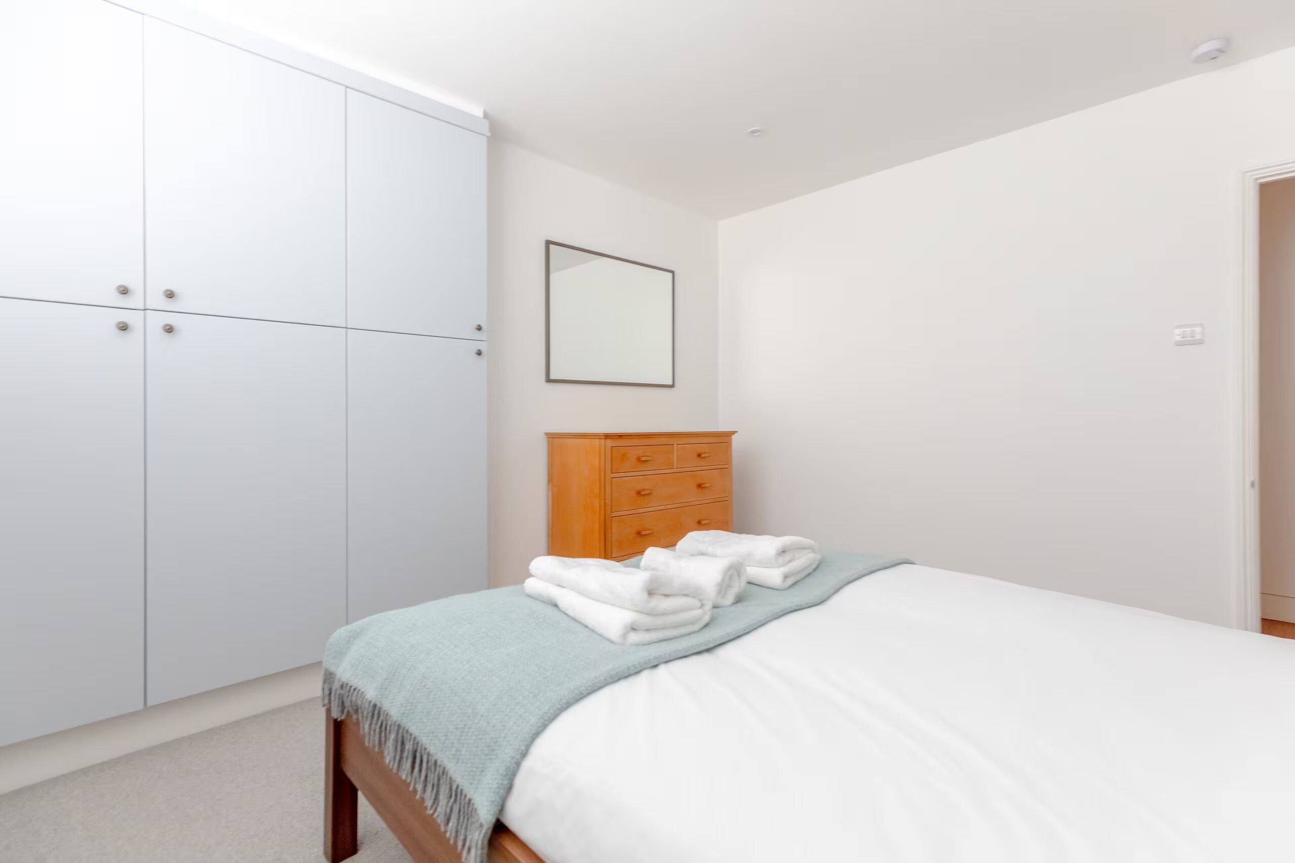A bedroom with a bed, a wardrobe, and a dresser.