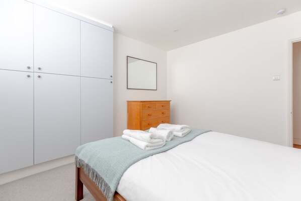 A bedroom with a bed, a wardrobe, and a dresser.