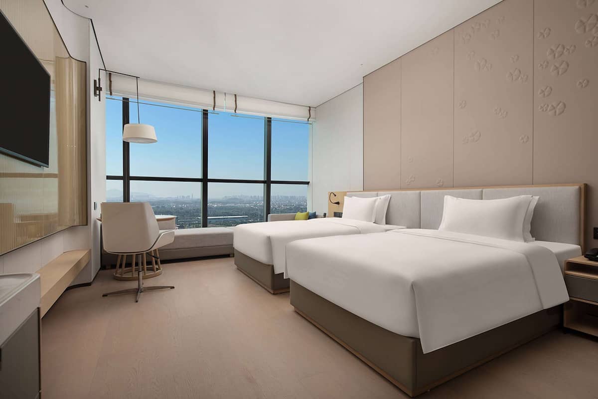 A modern hotel room with a large bed, a seating area, and a TV.