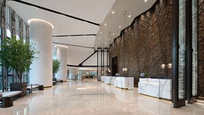 A spacious lobby with a reception desk, seating area, and a decorative wall. - Wyndham Foshan Nanhai (Foshan)