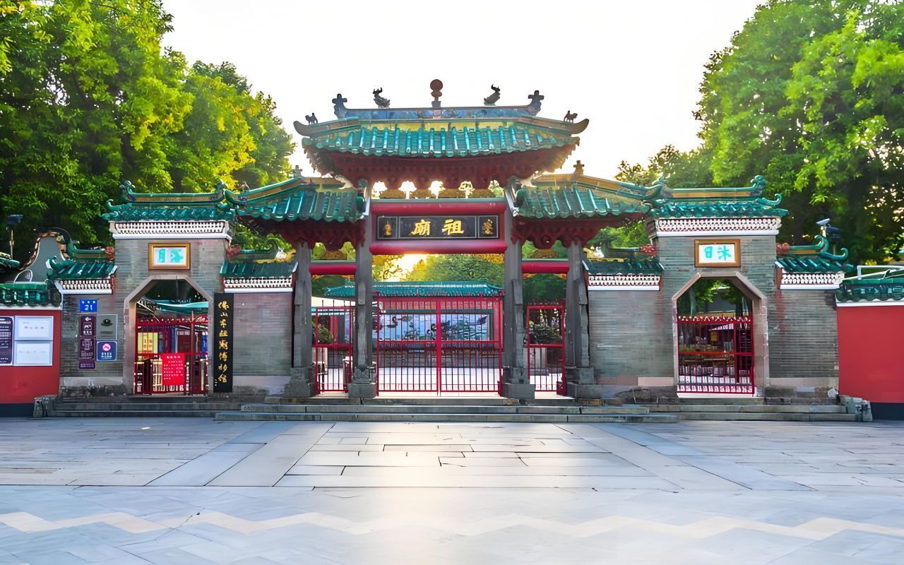 Une porte chinoise traditionnelle à l’architecture richement décorée, avec une arche centrale flanquée de deux arches plus petites, chacune surmontée d’une porte rouge.